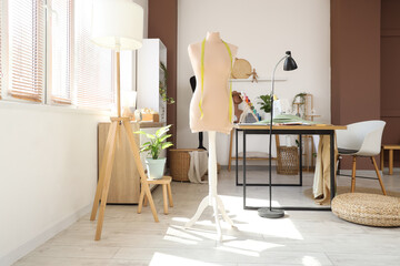 Interior of atelier with tailor's workplace, mannequin and plants