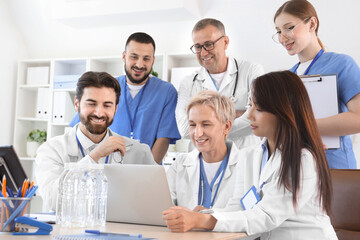 Fototapeta premium Team of doctors working with laptop at table in clinic