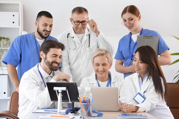 Fototapeta premium Team of doctors working with laptop at table in clinic