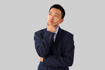 Dreaming Asian businessman on light background