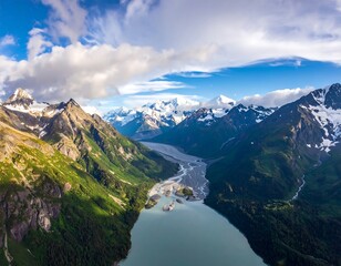 Expansive aerial view of a glacial lake valley, snow-capped peaks, and lush green mountain slopes