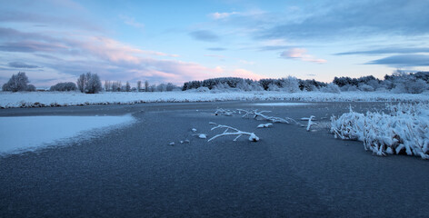 Frozen lake surrounded by snow under a cold winter sky. Quiet natural scenery with ice, frost, and seasonal atmosphere. West Lothian, Scotland