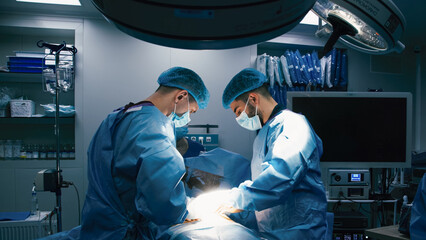 Two medical professionals in blue surgical scrubs performing a complex operation in a well-equipped operating room, showcasing teamwork and precision in a critical healthcare environment