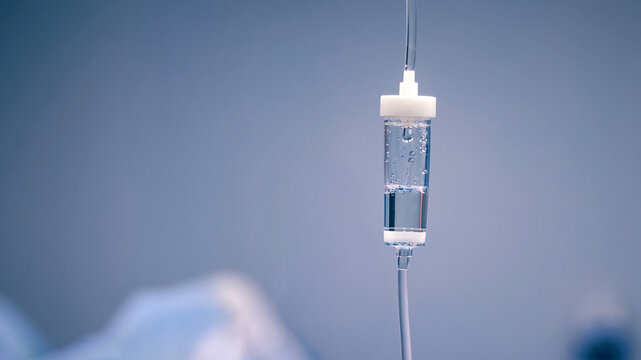 Medical IV drip bag suspended in a clinical setting, showcasing clear fluid and sterile environment, emphasizing healthcare and patient care concepts
