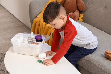 Little boy taking pills from table at home. Child in danger