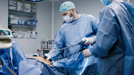 Male surgeon in blue surgical attire performing a minimally invasive procedure in a modern...
