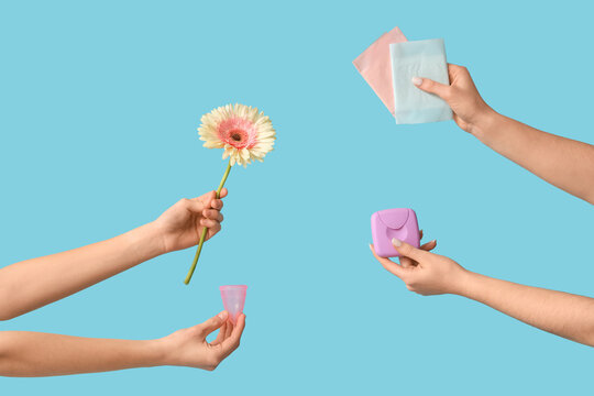 Female hands with menstrual cup, pads and tampons storage box on blue background
