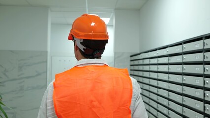Male construction worker in helmet and waistcoat walking in the building indoor on the construction...