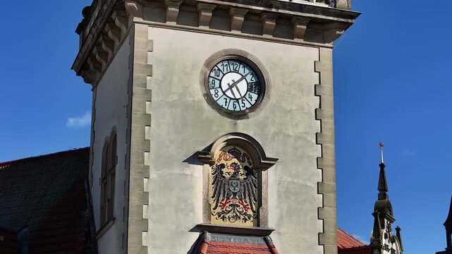 Slow drone flight in a half-circle around the clock tower of the post office at Horse Market in G&uuml;strow, Mecklenburg-Western Pomerania, showing historic architecture.