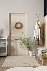 Fototapeta premium Door, clothes rack and vase with blossoming branches in stylish hall