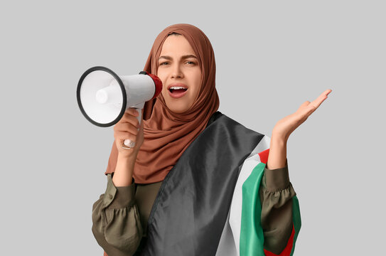 Young Muslim woman with Palestine flag and megaphone screaming on grey background. Sorrow concept