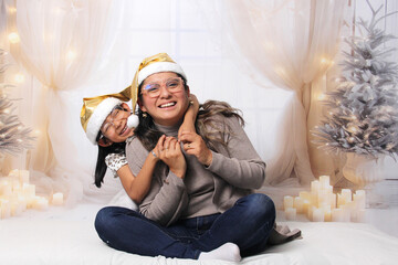 Naklejka premium Divorced single mother and her 5-year-old Latina daughter with glasses excited celebrate Christmas and New Year's together, wearing Santa hats
