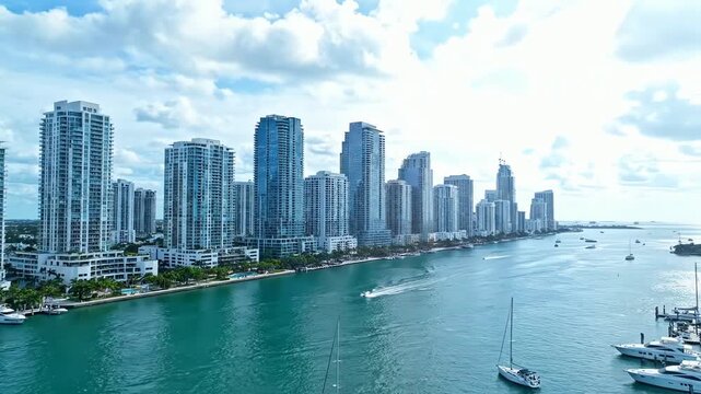 A breathtaking aerial hyperlapse of the Miami Florida skyline with modern skyscrapers, turquoise water, and boats on a bright sunny day