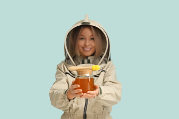 Female beekeeper with jar of sweet honey and dipper on blue background