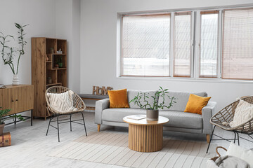 Stylish interior of living room with bamboo stems on coffee table and sofa