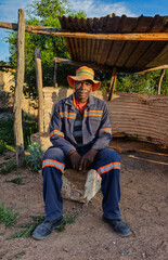 single african men sitting outdoors on a stone bench at sunrise, setting has corrugated metal and wooden supports