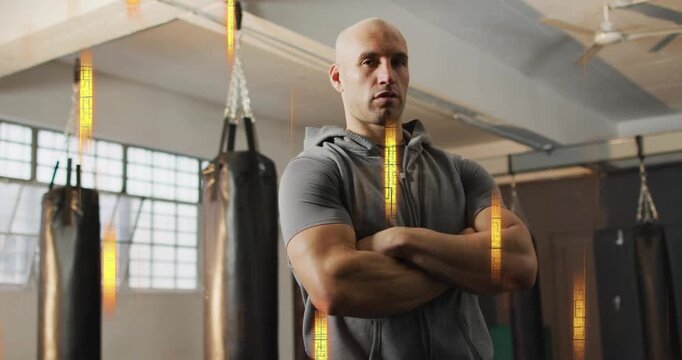 Trainer arms crossed in boxing gym, camera pulling back showing bags, golden streaks showing focus