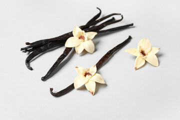 Aromatic vanilla sticks and flowers on grey background