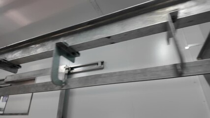Industrial stainless steel overhead rai, conveyor system with hooks and shackles inside a clean meat processing facility or slaughter house .