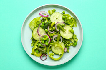 Plate of tasty vegetable salad on turquoise background