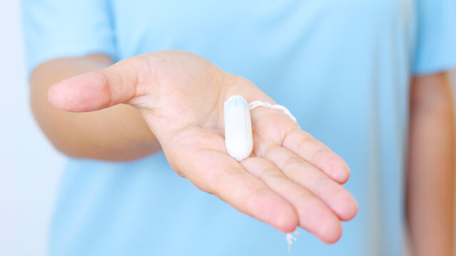Healthcare professional wearing blue scrubs holding tampon, representing feminine hygiene awareness and women's medical support - Powered by Adobe