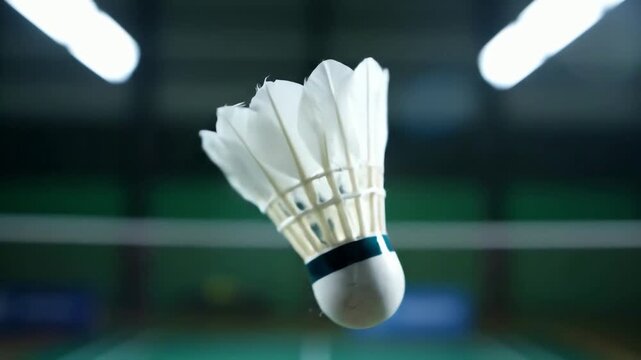 Cinematic slow motion close up of a badminton shuttlecock spinning in a seamless loop on a court.