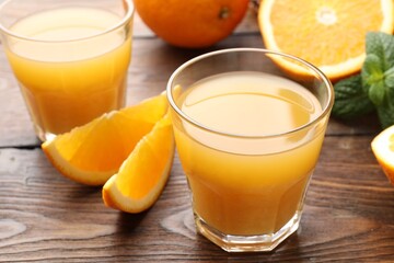 Fresh orange juice, mint and fruits on wooden table, closeup