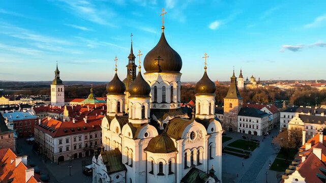 A breathtaking aerial view of a majestic white cathedral with dark domes in a historic European city at sunset