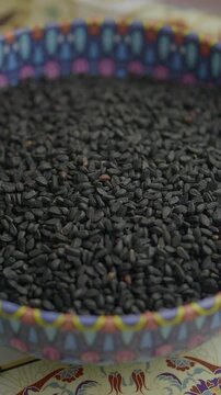 Pouring Black cumin seeds in a container 
