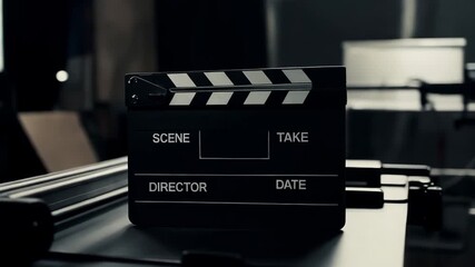 A close-up of an open, black-and-white clapperboard (slate) on a film dolly or production set, ready for filming, symbolizing cinema, video production, movie making, media, and the start of action.
