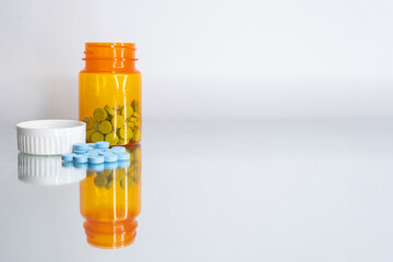 Prescription bottle with blue pills spilled on a mirror. Level view.