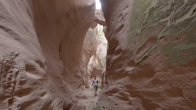 Man hiking through the narrow sandstone walls of Soganli Valley canyon in Cappadocia, Turkey