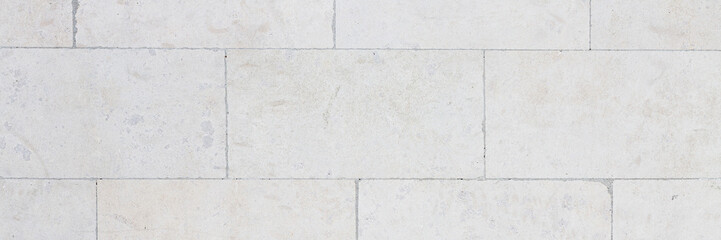 The texture of the wall, lined with light stone blocks. The polished surface of the masonry. Wide panoramic texture for background and design.