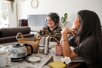 Mother and daughter are sitting at a table, one of them is wearing a striped shirt
