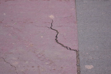 rough road, A crumbling asphalt road with a severely cracked and broken white line representing decaying infrastructure neglect and a difficult path or journey