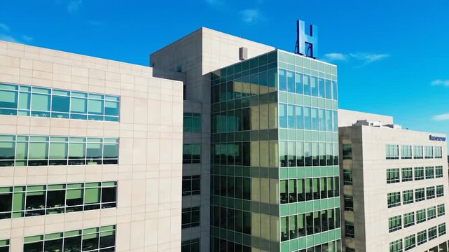 Contemporary hospital building with 'h' sign under clear blue sky.
