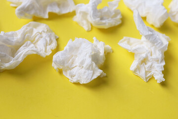 Used crumpled tissues scattered on a yellow surface.