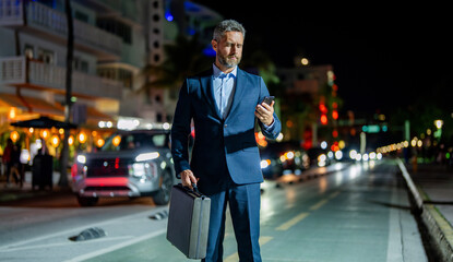 Businessman walking night city. Business man chat on phone outdoor. Businessman chatting on phone in night street. Businessman using smartphone. Successful businessman chatting online. Urban night
