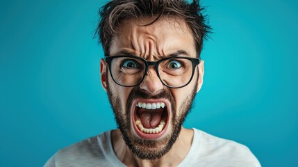 A man with glasses and a beard, wearing a white t-shirt, is screaming with his mouth wide open and his eyes wide open, against a blue background.