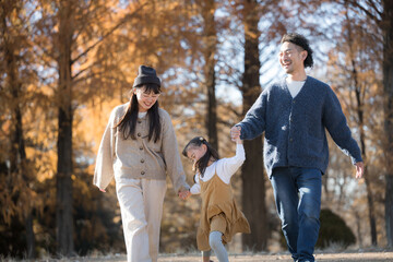 秋の公園で遊ぶ家族 お出かけやレジャーのイメージの手を繋ぐ	

