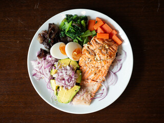 top view healthy dish of salmon steak with boiled egg, blanched carrots, spinach and ear mushroom, and fresh avocado and shallot