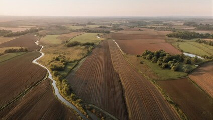 Obraz premium Aerial view of cultivated fields and winding road at sunset.