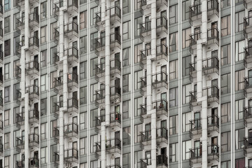 Modern high-rise apartment facade with repetitive windows and balconies offering an urban pattern texture.