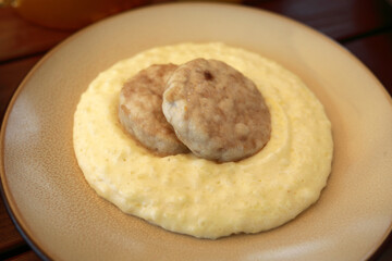 Two meat patties lie on bed of creamy polenta