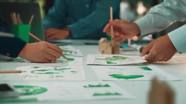 A business team collaborates on an eco-friendly project, analyzing charts and reports on sustainable practices in a modern office, highlighting teamwork and innovation efforts. SACTR