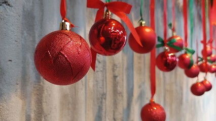 Holiday ornaments cascade gracefully, with brilliant crimson spheres and vibrant ribbons and festive flair against a softly textured wall.