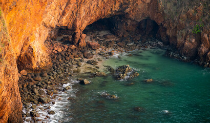 Sea cave at sunrise with golden light on rocky cliffs—ideal for scenic travel ads and nature-inspired wallpapers.