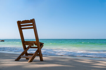 Solitary wooden chair on a tranquil beach—perfect for promoting nature retreats, coastal escapes, and mindful travel experiences.