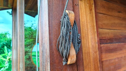 Traditional wooden block and tackle curtains hang in a villa, showcasing rustic charm and natural light filtering through the window.