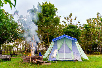 Camping tents at morning, vintage cabin tents, antique oil lamps, retro chairs, and a group of camping tents with outdoor coffee-making facilities on wooden tables in a forest camping area.